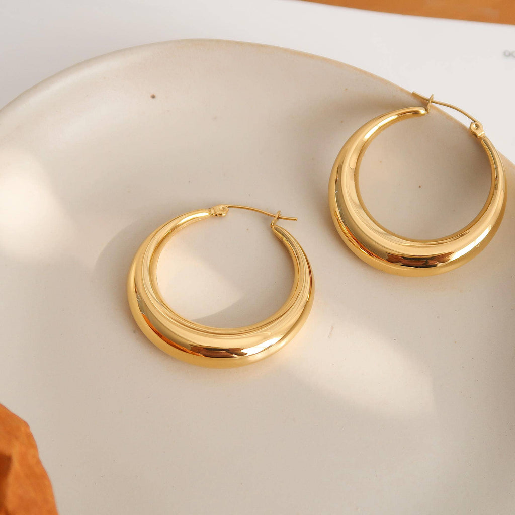 Gold hoop earrings on a white surface