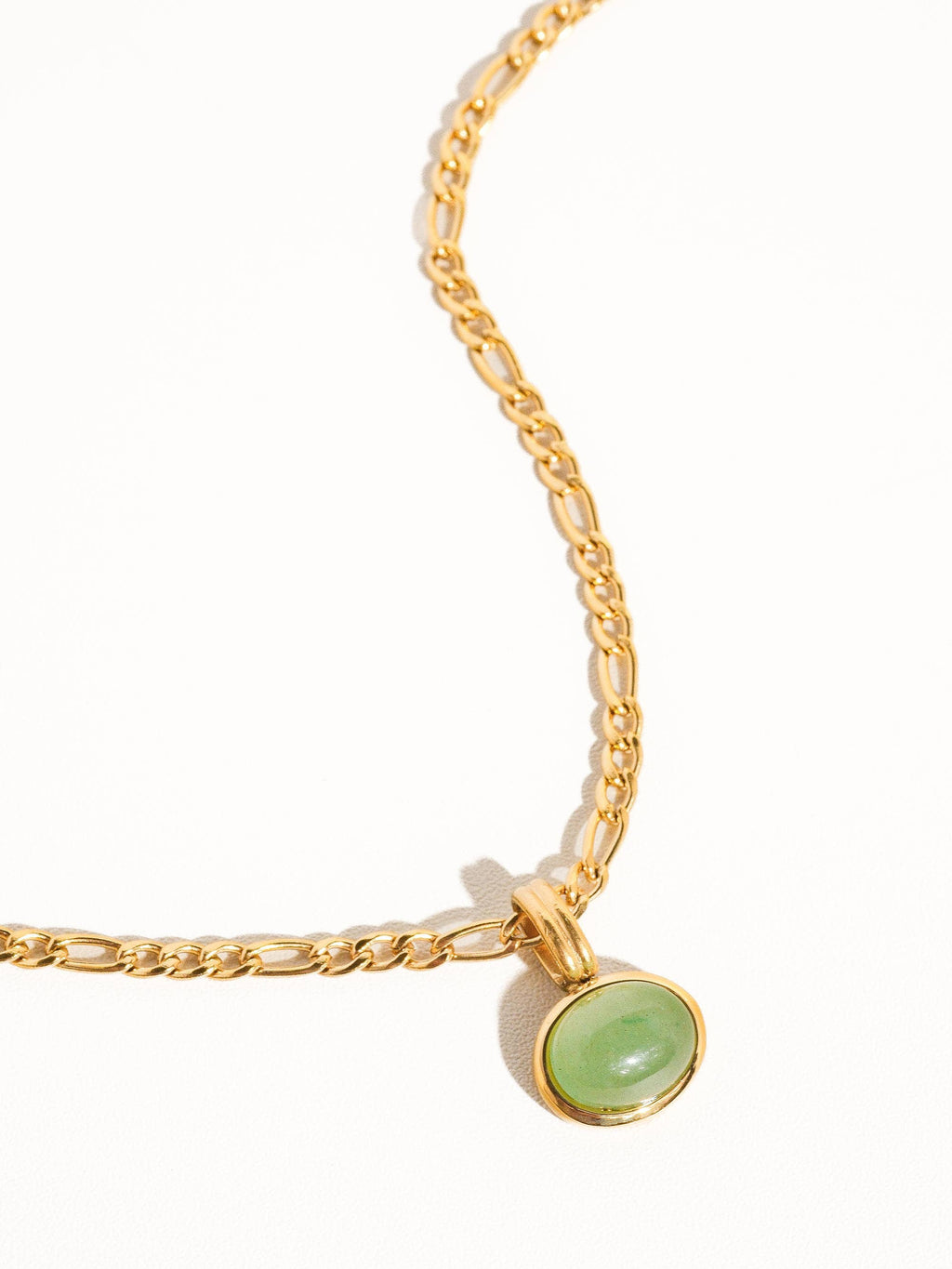 Gold chain bracelet with a green gemstone on a white background