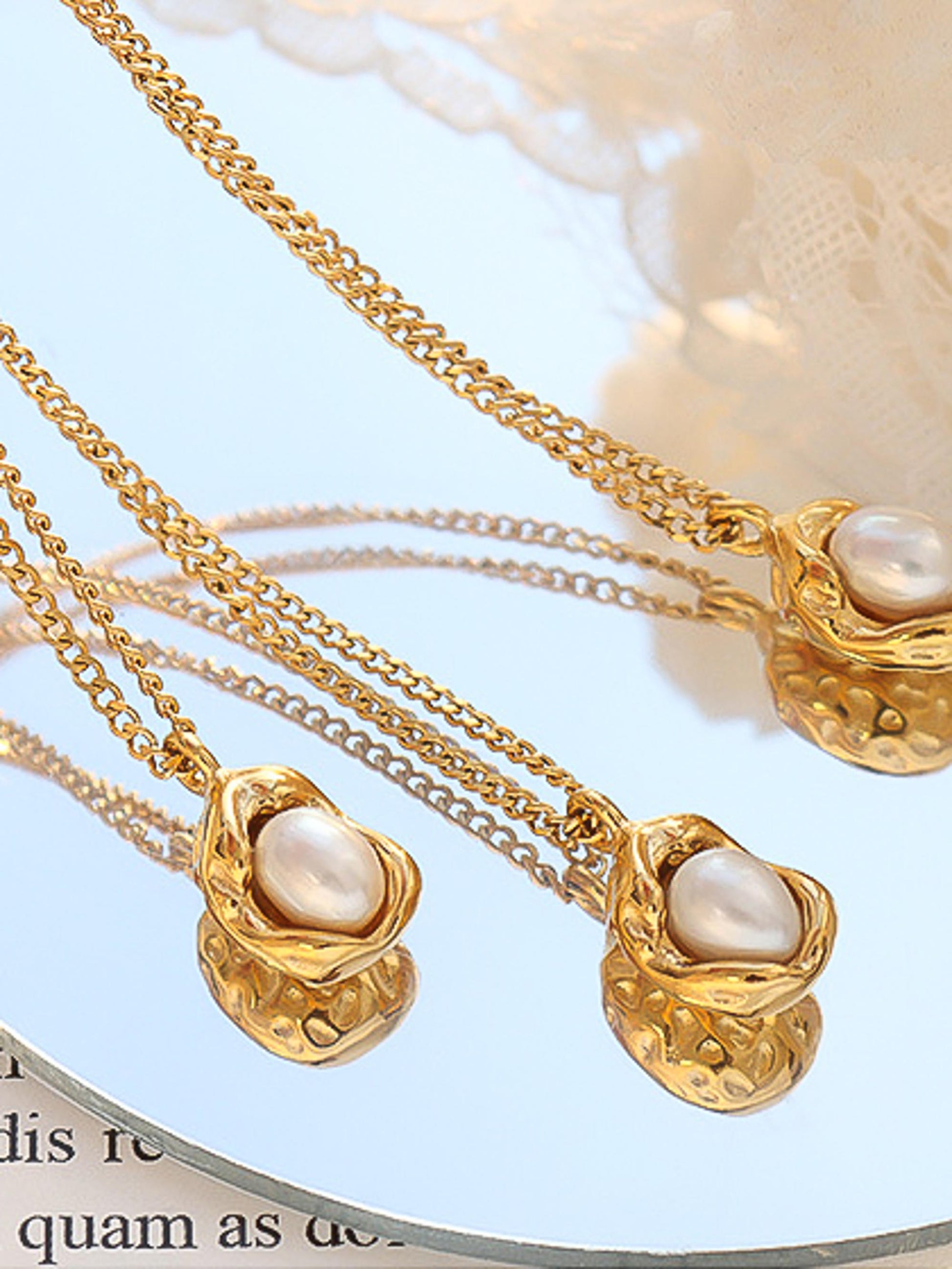 Gold necklaces with pearl pendants on a light blue background