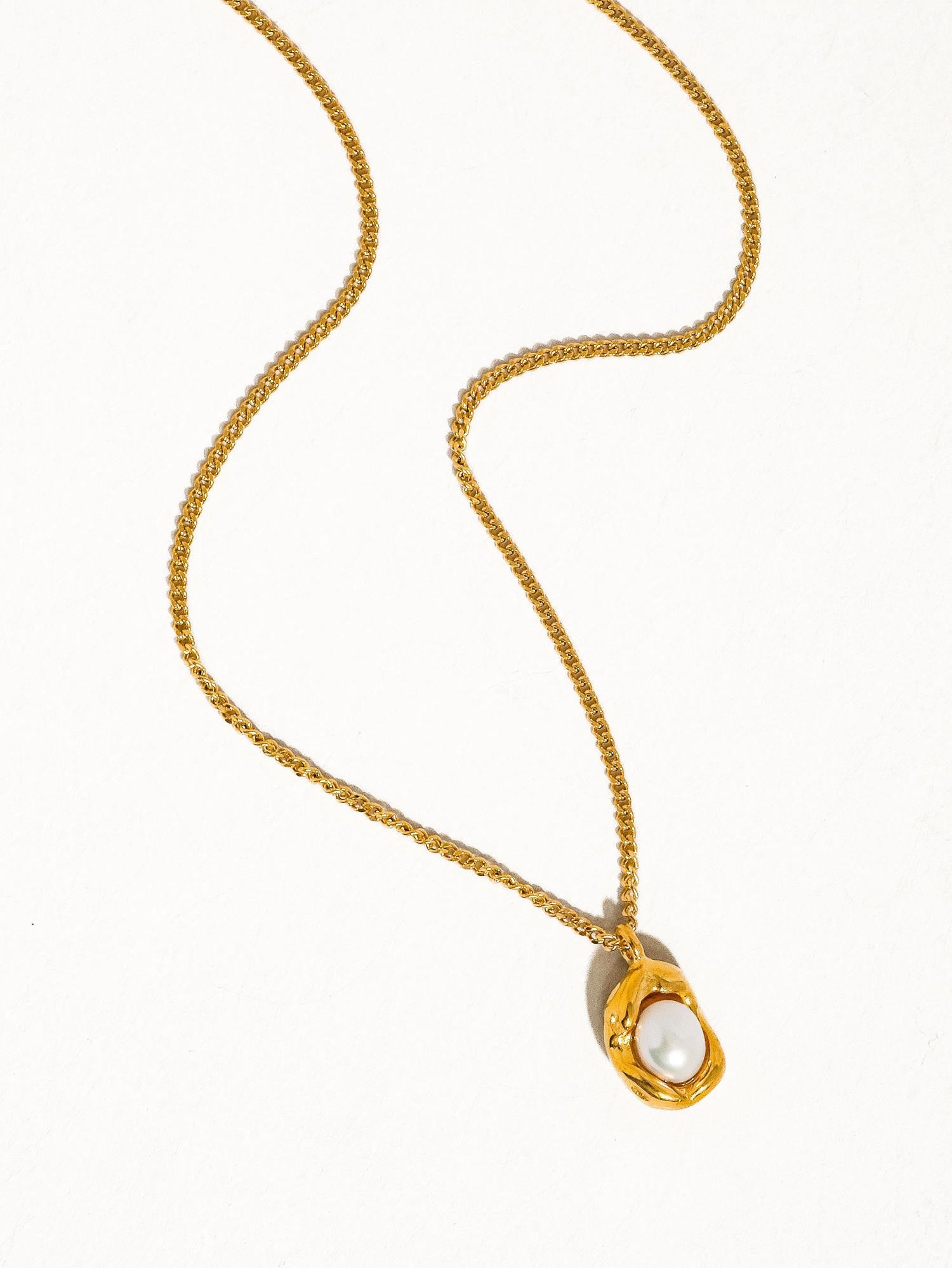 Gold necklace with a pearl pendant on a white background