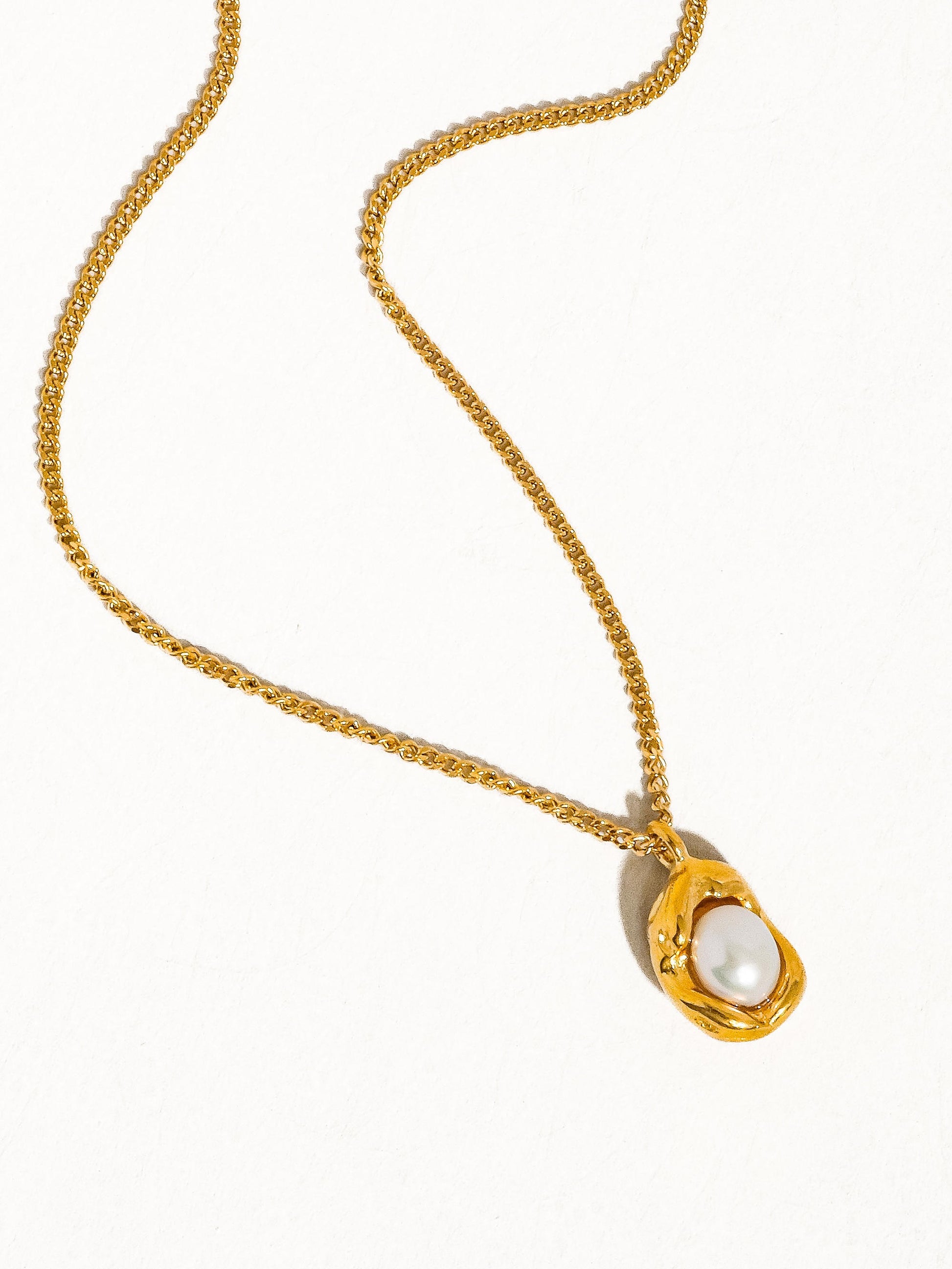 Gold necklace with a pendant featuring a pearl on a white background