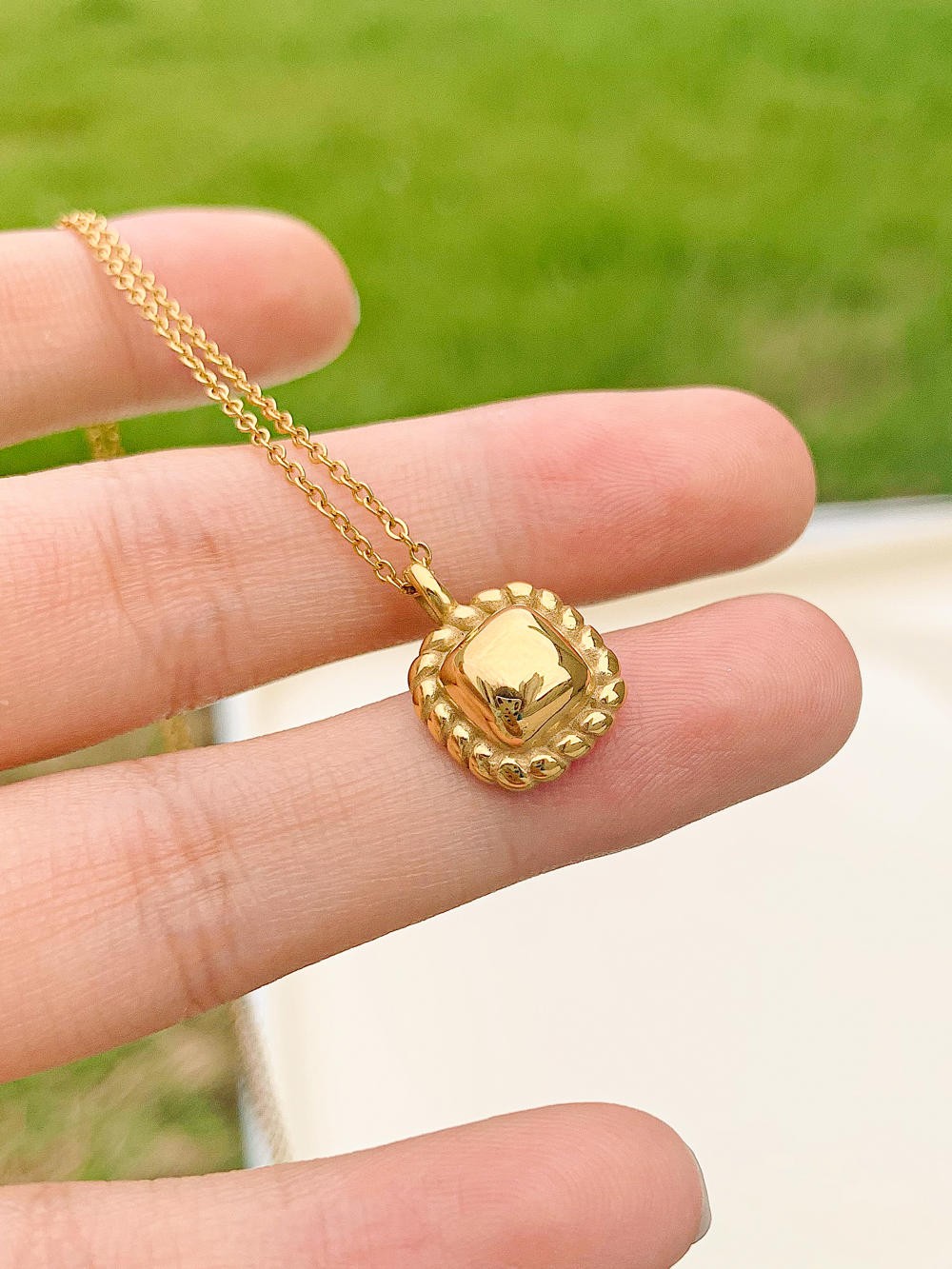 Classic petite square necklace on a model's hand. 