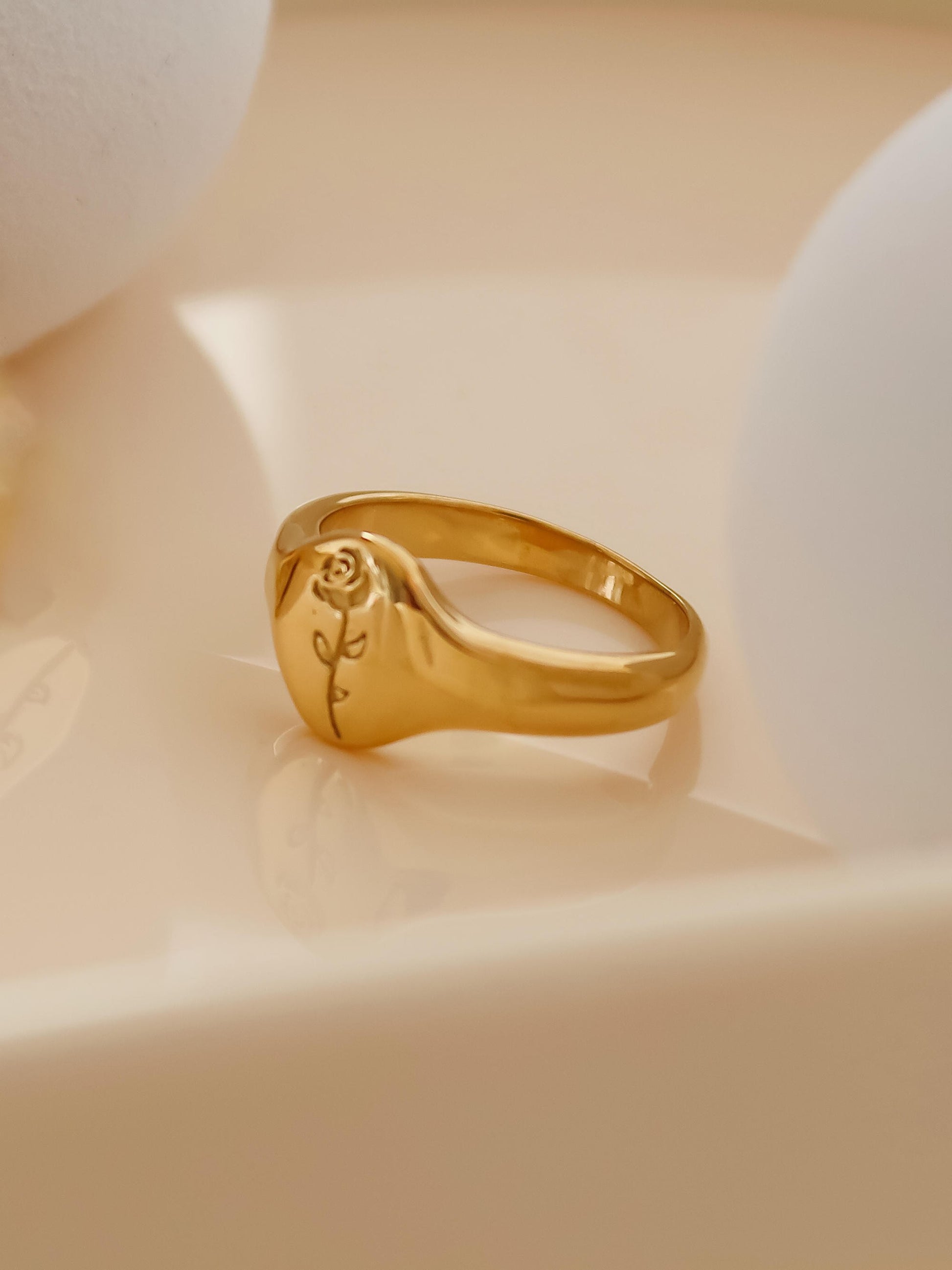 Gold ring with a rose design on a beige background