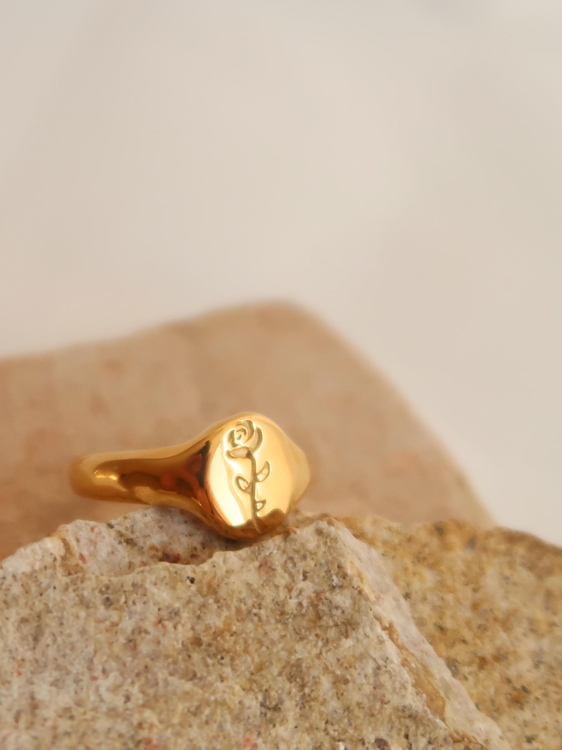 Gold ring with a rose engraving on a stone surface