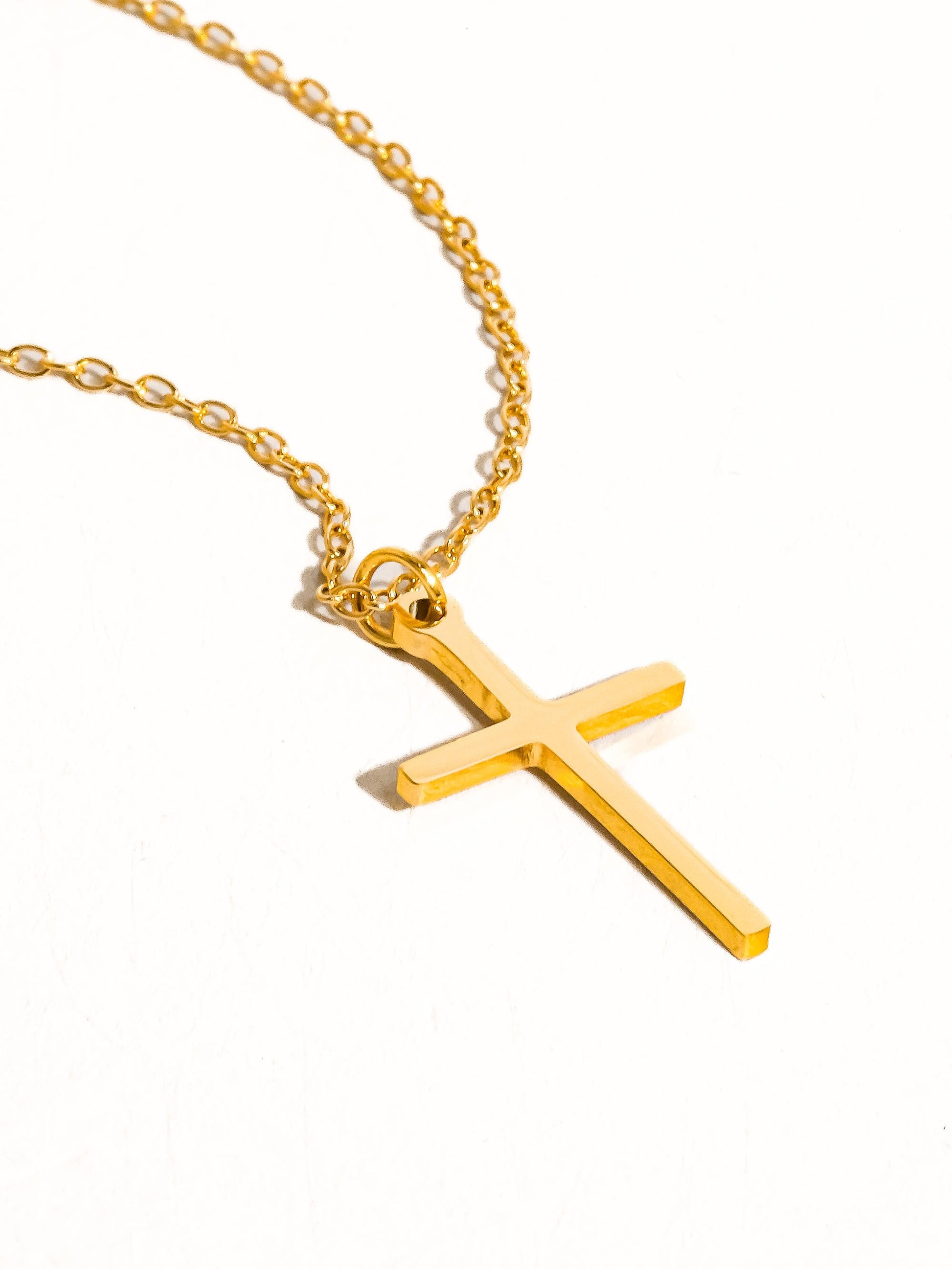Gold cross necklace on a white background