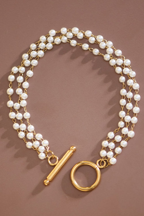 Pearl necklace with gold clasp on a brown background