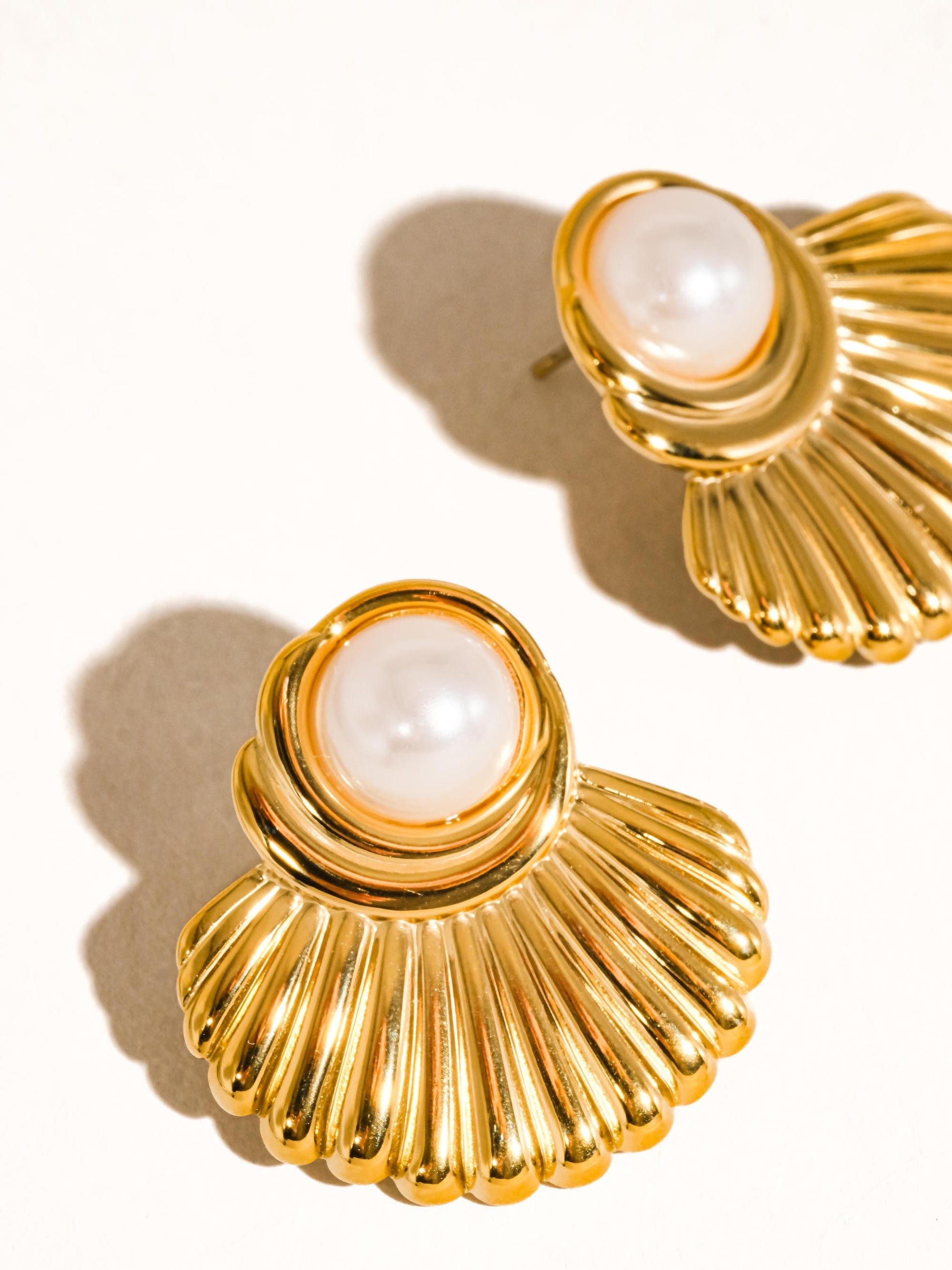 Gold earrings with pearl-like centers on a white background