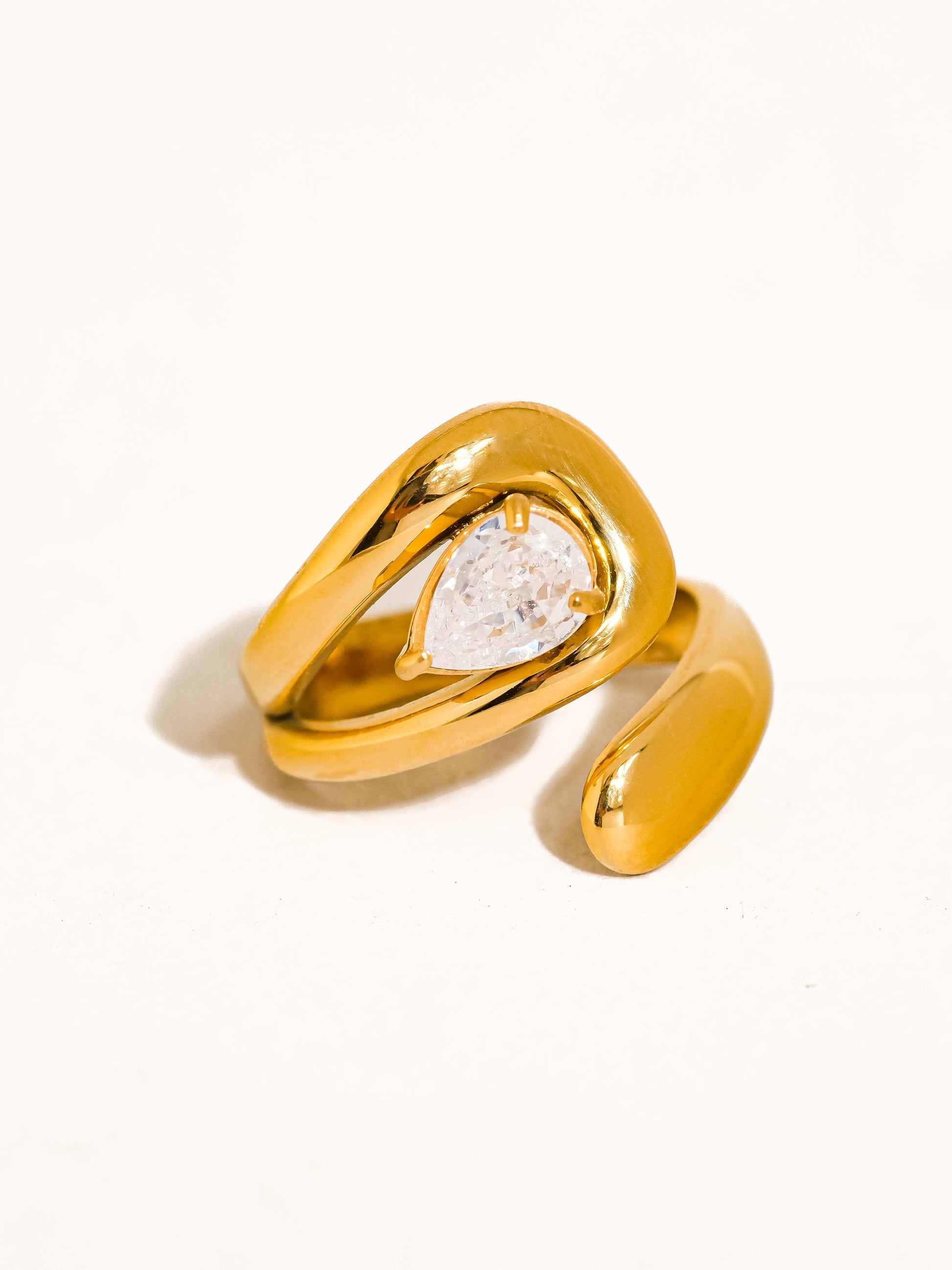 Gold ring with a pear-shaped diamond on a white background