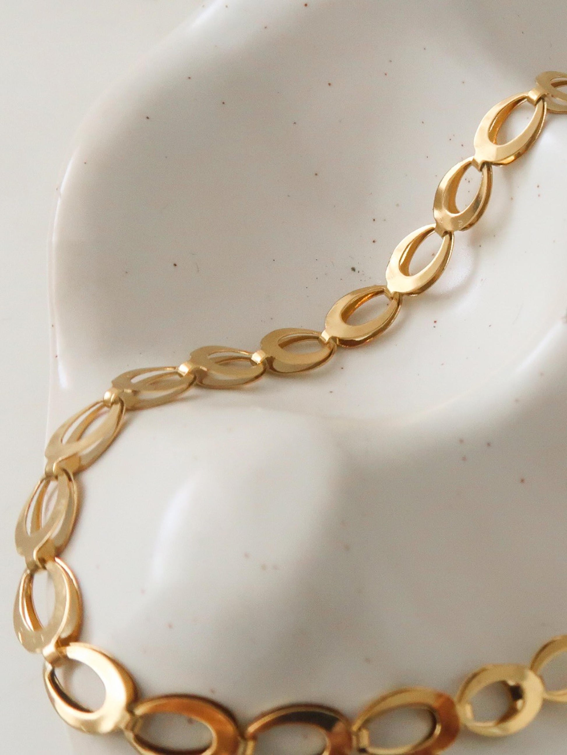 Gold chain bracelet on a white ceramic plate