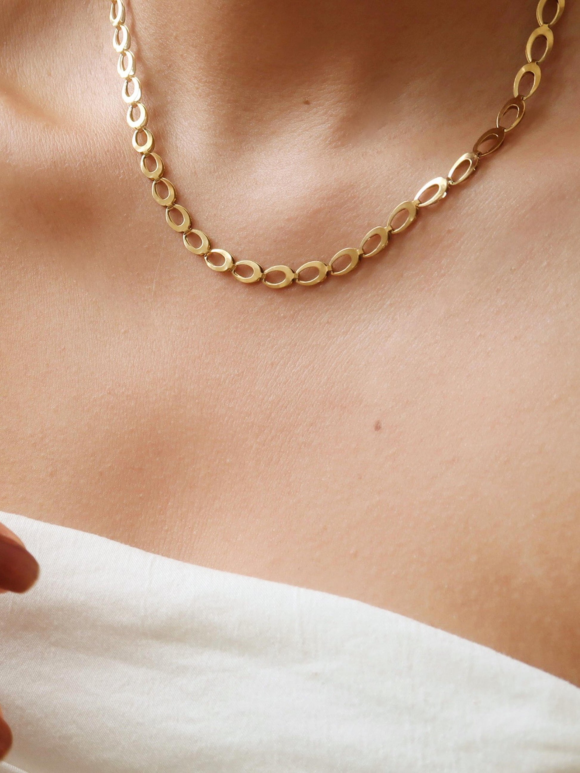 Gold chain necklace on a person's neck with a blurred background