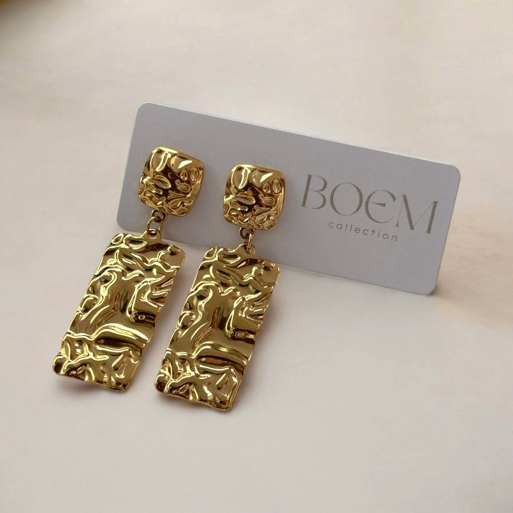 Gold earrings on a BOEM collection card against a light background