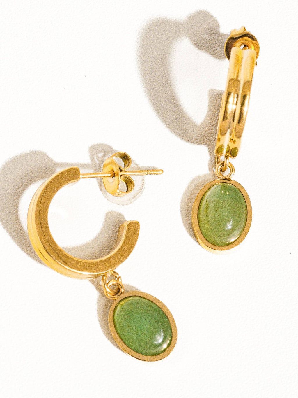 Gold hoop earrings with green stones on a white background