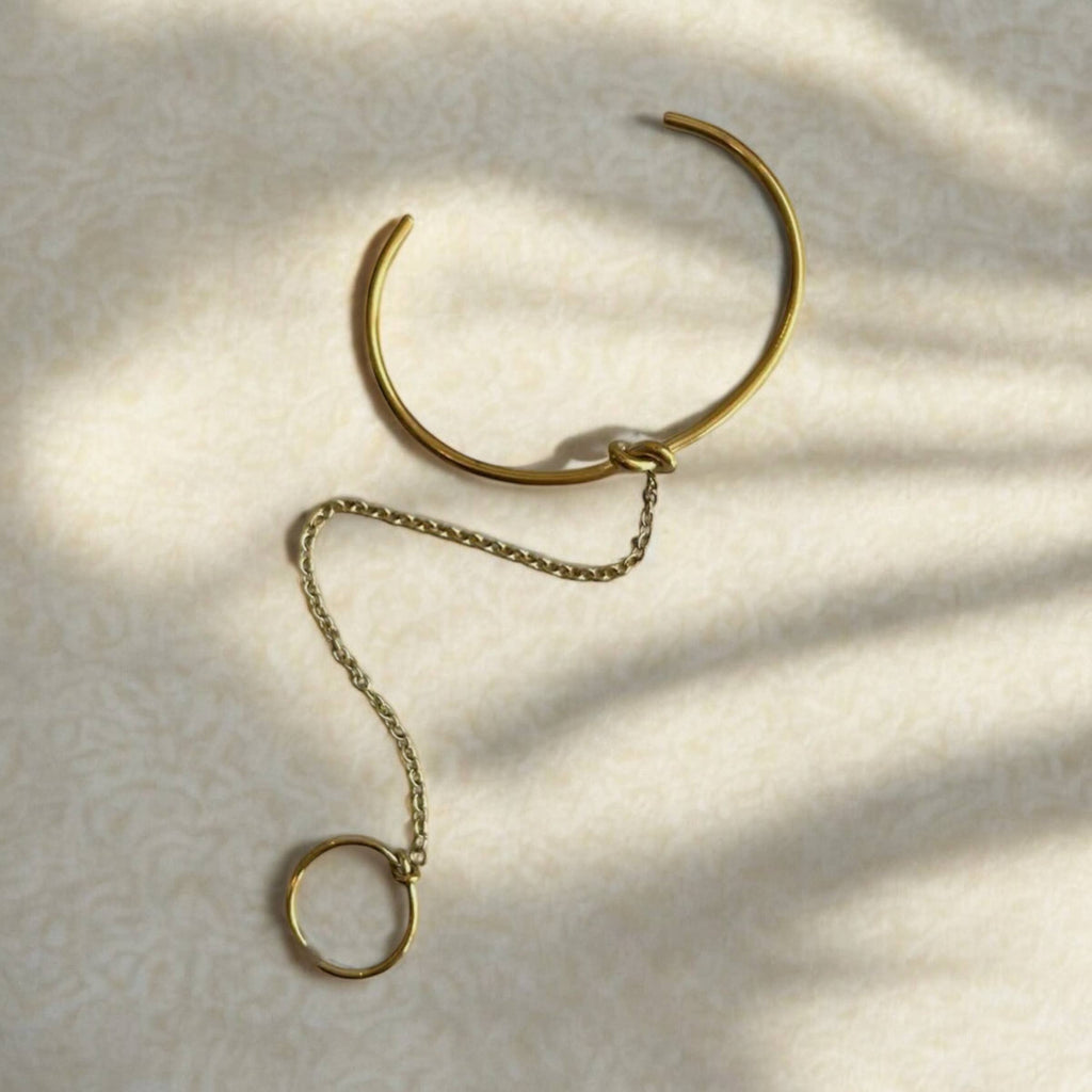 Gold bracelet with chain extension on a textured beige surface