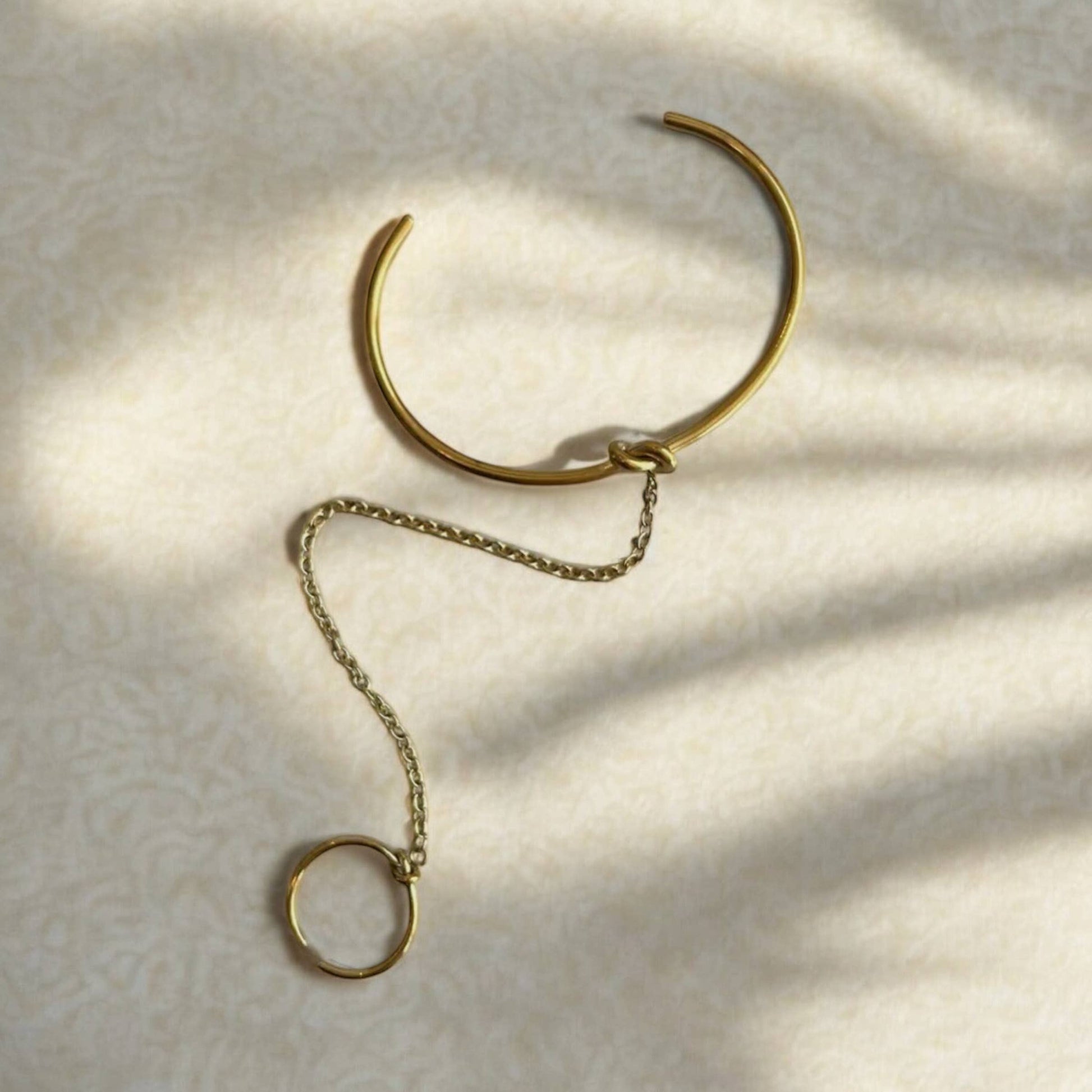 Gold bracelet with chain extension on a textured beige surface