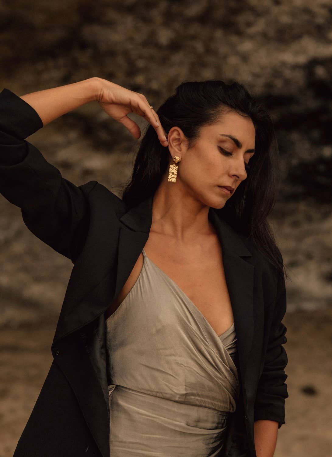 Woman adjusting her hair against a blurred natural background