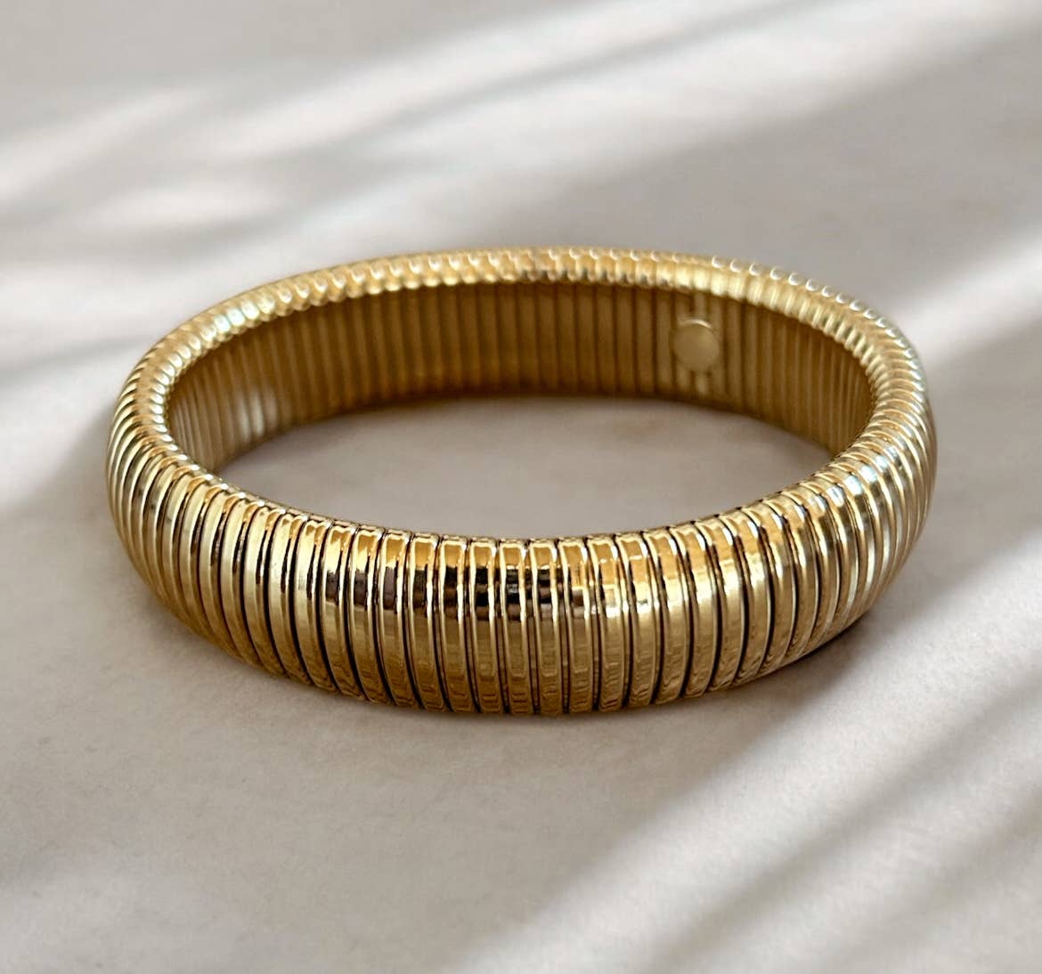 Gold bracelet on a light fabric background