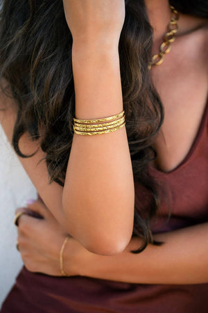Close-up of a person wearing gold bracelets on a blurred background