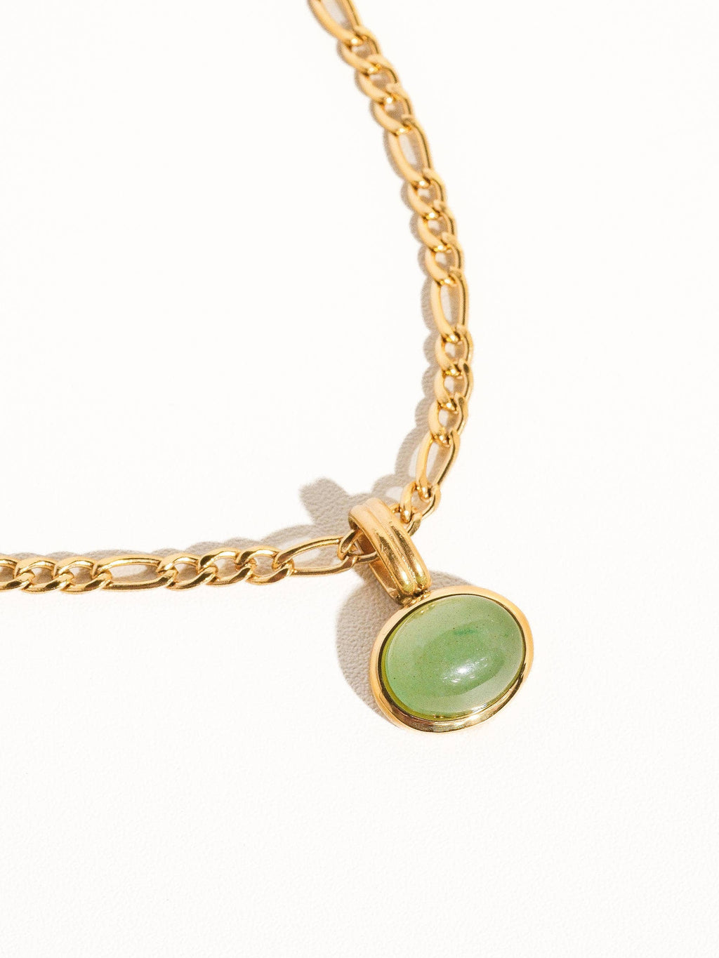 Gold necklace with a green gemstone pendant on a white background